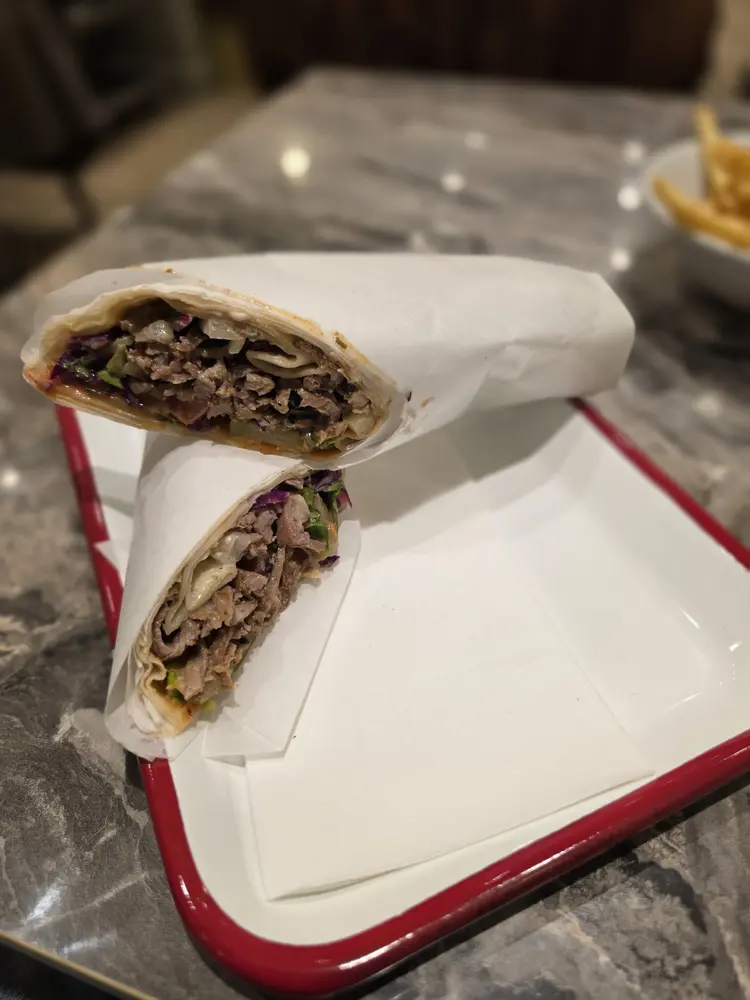 House-made lavash wrap filled with döner, salad and sauces, cut in half on a red tray